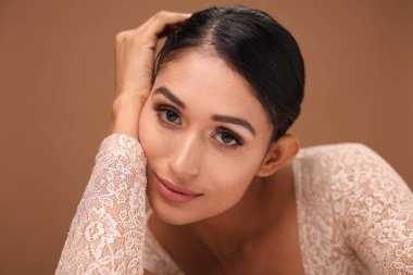 Genç, koyu renk saçlı bir kadın zarif pozlar veriyor. Parlak cildini gösteriyor. Cilt bakımı için mükemmel..