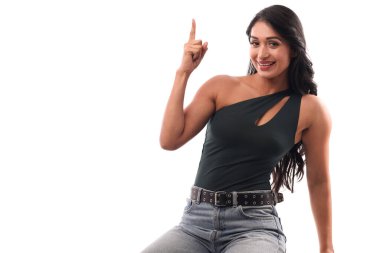 Gülümseyen güzel Asyalı kadın, stüdyo kahverengi izole edilmiş arka planda boş bir yeri işaret ediyor..