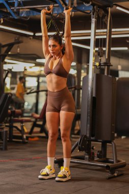 Siyah spor giyim giymiş bir kadın odaklanma ve kontrolle trisepsi uzatıyor..