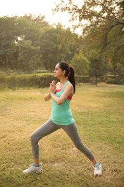 Bir kadın yoga pratiği yapıyor. Sakin ve odaklanmış bir ifadeyle poz veriyor. Güç ve sükuneti somutlaştırıyor..