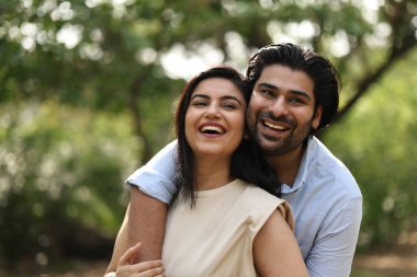 Mutlu çift gün içinde yeşil bir parkta sarılıp gülüyor..