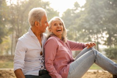 Yaşlı bir çift birbirine yakın oturuyor, altın saat boyunca sakin bir açık havada kahkahalarını paylaşıyorlar..