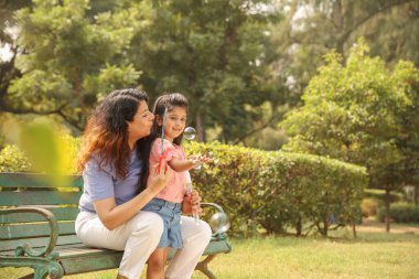 Parkta sabun köpükleriyle eğlenen Hintli bir anne ve kızın görüntüsü..