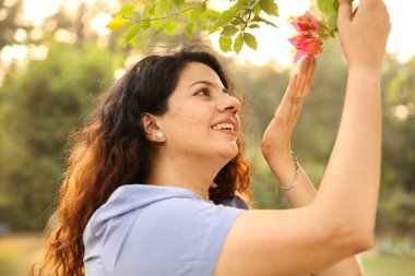 Çekici bir dişi gülümsüyor ve arka plandaki çiçeğe bakıyor..