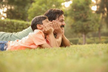 Baba ve oğul resimlerinde ikisi de parkta uzanmış, geleceğe bakıyor..