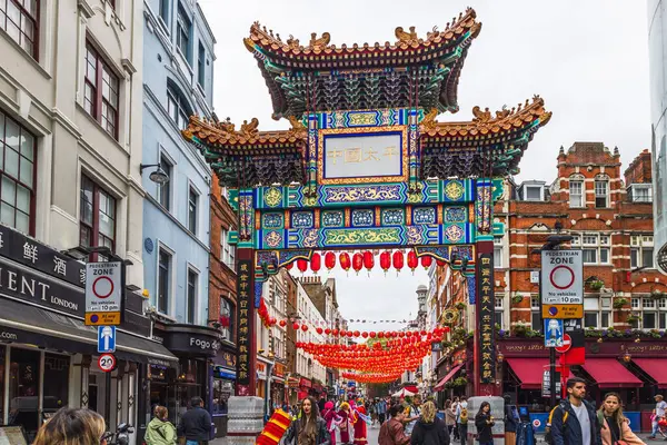 Londra 'daki Çin Mahallesi kapısının canlı renklerini ve geleneksel tasarımını yakalayın. Hareketli sokak sahnesi hareketli bir atmosfer yaratıyor. Londra, İngiltere, 21 Mayıs 2023