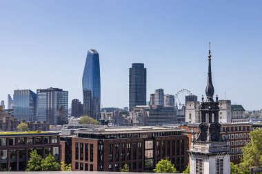 Londra şehri modern gökdelenleri ve tarihi binaları berrak mavi bir gökyüzü altında harmanlıyor.
