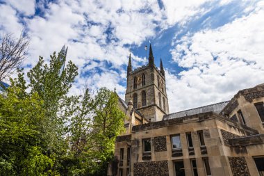 Southwark Cathedral in London showcasing historic Gothic architecture, a towering spire, and lush greenery clipart