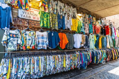 Portobello Road Market 'teki açık hava tezgahında gösterilen renkli kıyafetlerden oluşan canlı bir seçim, benzersiz bir sokak modası sergiliyor. Londra, İngiltere, 25 Haziran 2023