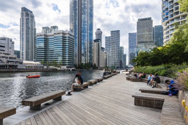 Londra 'daki Kanarya İskelesi' nde çarpıcı bir ufuk çizgisi, ahşap deniz kenarı gezinti alanı ve yemyeşil yemyeşil koltuklar bulunuyor.