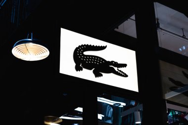 Elegant Lacoste storefront logo displayed against a sleek black background, symbolizing luxury and sophistication. London, UK, 4 July 2023 clipart