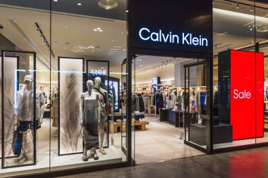Zarif Calvin Klein mağazası vitrininde mankenler, modern ışıklandırma ve koyu kırmızı bir satış tabelası var. Londra, İngiltere, 4 Temmuz 2023