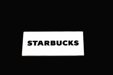 Starbucks mağaza önü logosu, lüks ve sofistike olduğunu sembolize eden parlak siyah bir arka planda sergileniyor. Londra, İngiltere, 4 Temmuz 2023