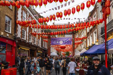 Canlı bir Çin Mahallesi caddesi kırmızı fenerler ve şenlikli süslemelerle süslenmiş, canlı atmosferin tadını çıkaran insanlarla dolu. Londra, İngiltere, 16 Temmuz 2023