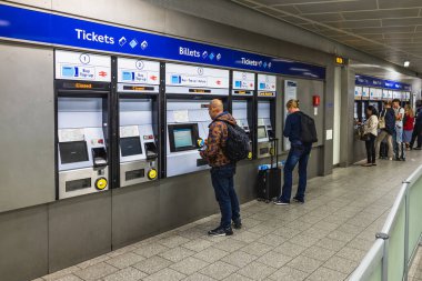 İnsanlar Londra metro istasyonunda bilet makineleri kullanıyorlar, İngiltere 'de yoğun bir toplu taşıma merkezi.