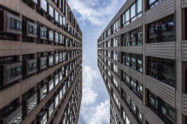 Symmetrical vertical view of two modern buildings framing a bright sky, showcasing urban architecture and design clipart