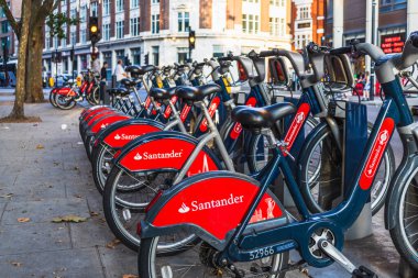 Kırmızı Santander bisikletleri halka açık bir rıhtım istasyonuna düzgün park etmiş, sürdürülebilir kentsel ulaşımı teşvik ediyor. Londra, İngiltere, 2 Eylül 2023