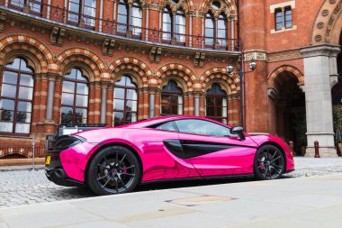 Lüks pembe hiperaraba, St Pancras Oteli 'nin karmaşık Victoria mimarisine karşı yan yana. Londra, İngiltere, 1 Ekim 2023