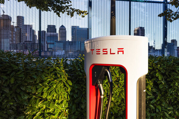 Станция Tesla Supercharger в городской обстановке на фоне городского пейзажа. Лондон, Великобритания, 14 октября 2023 года
