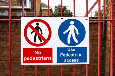 Şehir merkezindeki kırmızı metal bir çite asılmış yaya geçidi ve yaya geçidi yok..