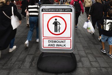 Kalabalık halk yolunda oturmayı yasaklayan bir işaret, yayaları ayağa kalkmaya teşvik.