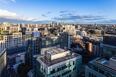 Gökdelenleri, ofis binaları ve mavi gökyüzünün altındaki yerleşim kuleleri olan modern bir şehrin gökyüzü manzarası. Londra