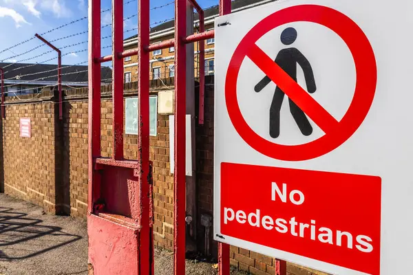 Kırmızı güvenlik çitine asılmış yaya uyarı levhası özel bir bölgeye erişimi kısıtlıyor..