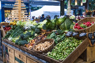 Londra Borough Market 'teki bir gıda standında turistlerin ve yerlilerin ilgisini çeken bir dizi taze sebze. Londra, İngiltere, 17 Aralık 2023