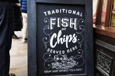 Geleneksel İngiliz balık ve patates kızartması tabelası bir restoranın dışındaki tahtada sergileniyor ve taze gıdanın reklamını yapıyor. Londra, İngiltere, 17 Aralık 2023