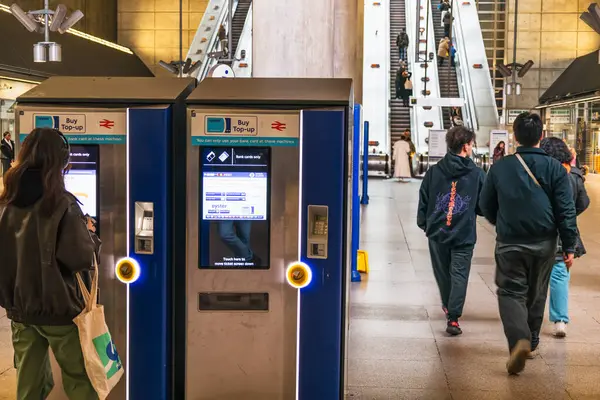 Modern bir yeraltı istasyonunda insanların geçtiği bilet otomatları. Londra, İngiltere, 24 Aralık 2023