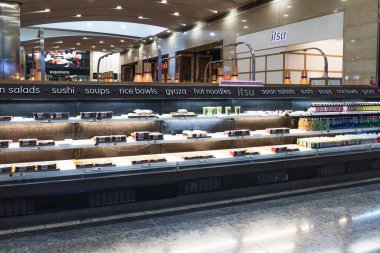 Aydınlatılmış tezgahı ve çeşitli suşi ruloları olan modern taşıma bandı suşi restoranı. Londra, İngiltere, 24 Aralık 2023