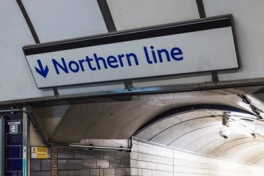 Londra metro tünelinde temiz modern tasarım ile yön işareti.