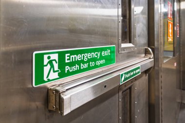 Yeşil acil çıkış işareti ve metal kapıdaki çubuk, metroda kamu güvenliği erişimi.