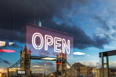 Neon tarzı OPEN işareti, arka planda Tower Bridge ile birlikte cama yansıdı