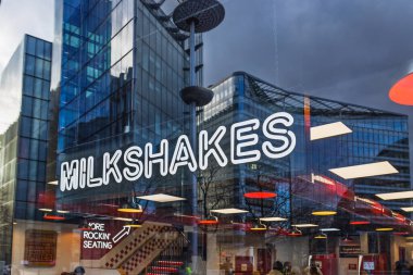 Neon Milksshake tabelası şehir manzarasında modern bir cam mağazasında parlıyor. Londra, İngiltere, 14 Ocak 2024