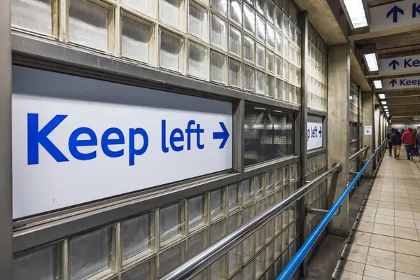 Londra metro istasyonunun koridorundaki fayanslı bir duvarda sol işaret tutun..
