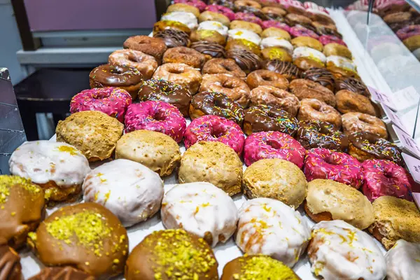 Pastane vitrininde renkli kremalı, kremalı ve soslu leziz donutlar..
