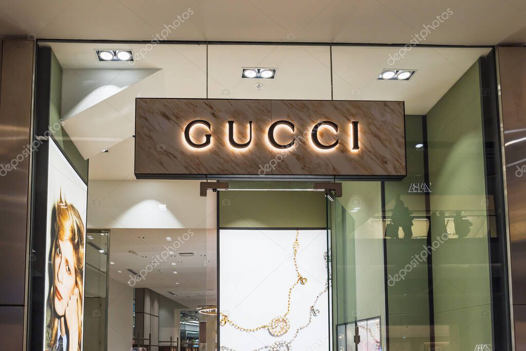 Gucci store entrance featuring illuminated signage and elegant glass design in a modern shopping mall. London, UK, 10 February 2024