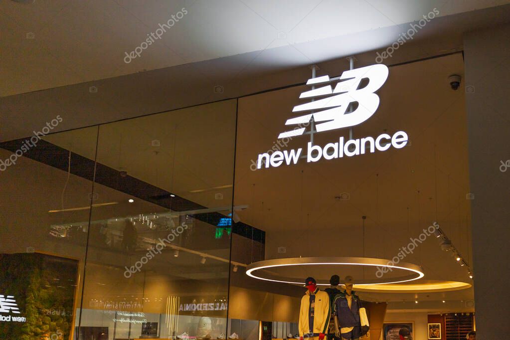New Balance retail store entrance with illuminated NB logo signage inside a contemporary shopping mall. London, UK, 10 February 2024
