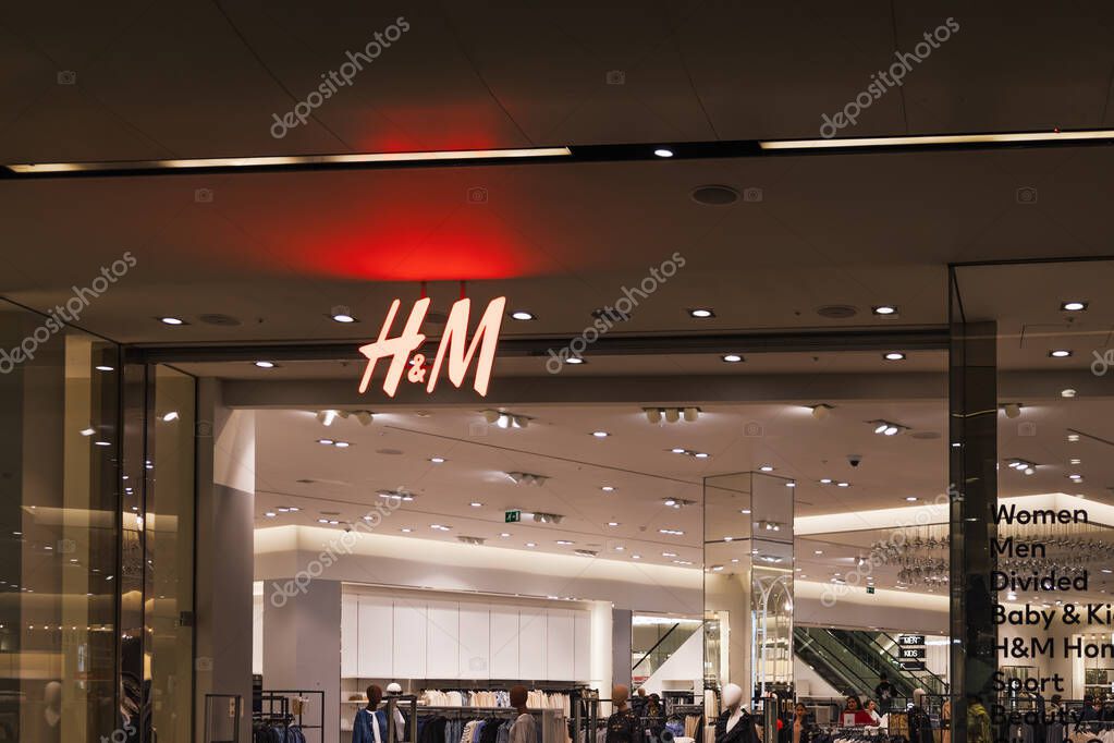 H M storefront with iconic red logo and illuminated signage in a bright and modern shopping mall interior. London, UK, 10 February 2024