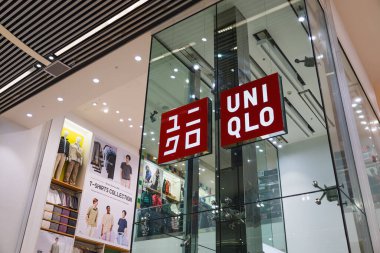 Aydınlatılmış UNIQLO mağazası cam cephede parlak kırmızı bir tabela, popüler küresel moda perakende markası sergileniyor. Londra, İngiltere, 10 Şubat 2024