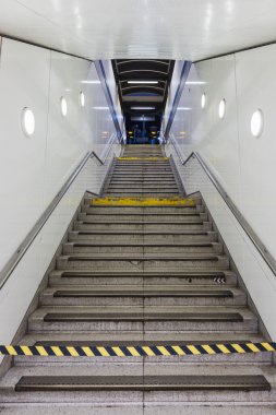 Metro istasyonuna inen merdiven tırabzanlar, parlak ışıklar ve güvenli banliyö girişi için sarı uyarı şeritleriyle donatılmış..