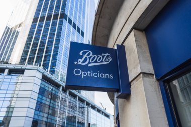 Boots Opticians, şehir binalarının yansımalarıyla dolu işlek bir kentsel ortamda yer alan cesur mavi tabela ve modern cam cepheleriyle mağaza önündeydi. Londra, İngiltere, 11 Şubat 2024