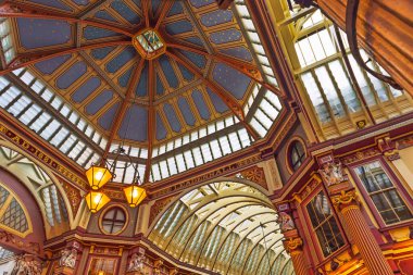 Londra 'daki Leadenhall Market' in göz kamaştırıcı iç mekanında süslü demirler, renkli cam çatı ve tarihi bir alışveriş salonunda sıcak kaliteli ışıklandırma sergileniyor. Londra, İngiltere, 11 Şubat 2024