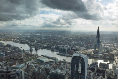 Londra 'nın göz kamaştırıcı gökdeleniyle gökdelenler ve Thames nehri dramatik bulutlu gökyüzünün altında dalgalanırken görüntüsü..