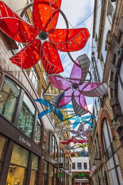 Açık hava kelebek sanat kurulumu. Dar, büyüleyici bir şehir geçidinde ışık ve mimari detaylarla dolu canlı renkler asılı. Londra, İngiltere, 11 Şubat 2024