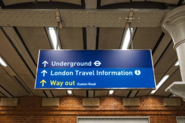 Londra metrosuna giden yolcuları yönlendiren mavi tabela, bilet bilgileri ve çıkış yolu..
