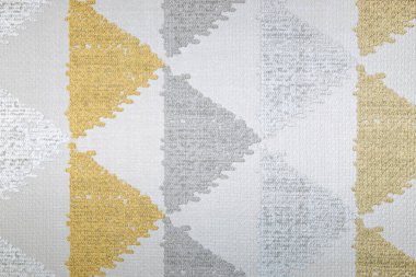 Yumuşak gri ve hardal sarısı tonlarda geometrik üçgenlerle dokunmuş kumaş dokusu..