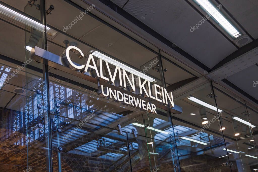 Exterior close up of Calvin Klein storefront with illuminated logo on glass in luxury mall. London, UK, 25 February 2024