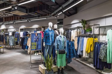 Modern bir giyim mağazasının içinde renkli ceketler ve ahşap raflarda günlük kıyafetler sergileniyor. Londra, İngiltere, 25 Şubat 2024